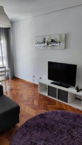 sala de estar con TV de pantalla plana en un centro de entretenimiento blanco en Apartamento Julia en Vilagarcía de Arousa