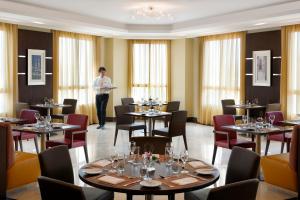 a man standing in a restaurant with tables and chairs at Marriott Executive Apartments Riyadh, Convention Center in Riyadh