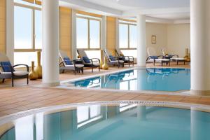 una piscina nella hall dell'hotel con sedie e tavoli di Marriott Executive Apartments Riyadh, Convention Center a Riyad