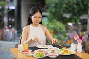 uma mulher a preparar comida numa mesa com pratos de comida em Señorita Boutique Hotel em Da Nang