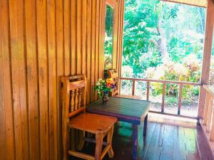 a wooden table and chair in a room with a window at Lanta Maikeaw Bungalow in Ko Lanta