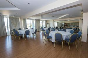 a banquet hall with white tables and blue chairs at Dolphin Resort & Conference in Kalamos