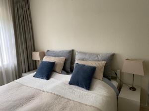 ein Schlafzimmer mit einem großen Bett mit blauen Kissen in der Unterkunft Lonestar Appartement in Burgh Haamstede