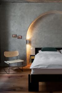 1 dormitorio con 1 cama y 1 silla en Ein Kraftort und architektonisches Juwel, en Ardez