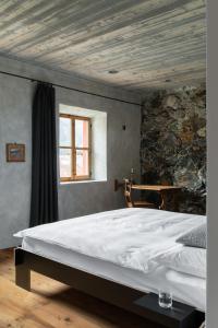 1 dormitorio con 1 cama blanca grande y pared de piedra en Ein Kraftort und architektonisches Juwel, en Ardez