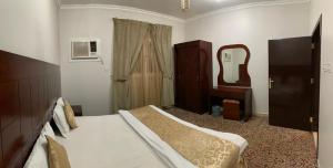 Schlafzimmer mit einem Bett, einer Kommode und einem Spiegel in der Unterkunft رسلين للشقق المخدومة in Ha'il