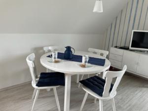 einen weißen Esstisch mit Stühlen und einen TV in der Unterkunft Wattnest - Ferienwohnung direkt in erster Meereslinie am Deich in Friedrichskoog