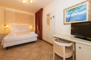 a bedroom with a bed and a desk with a television at Bertoletta Village Apartments in Peschiera del Garda