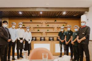 um grupo de homens usando máscaras faciais em uma cozinha em Hotel Myriad em Lucknow