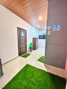 ein leeres Zimmer mit grünem Teppichboden und einer Tür in der Unterkunft Noel's beach homestay in Alappuzha
