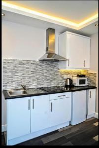 a white kitchen with a sink and a microwave at The Lily Aparts in London