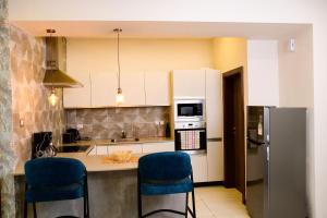 a kitchen with white cabinets and blue bar stools at Exquisite 2BD at Skynest Residences with rooftop heated pool in Nairobi