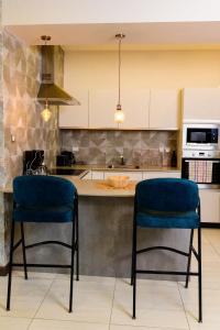 een keuken met twee blauwe stoelen voor een aanrecht bij Exquisite 2BD at Skynest Residences with rooftop heated pool in Nairobi
