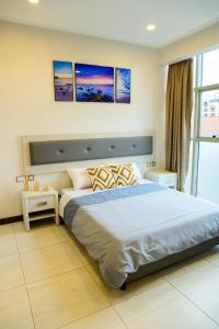 a bedroom with a large bed with three paintings on the wall at Exquisite 2BD at Skynest Residences with rooftop heated pool in Nairobi