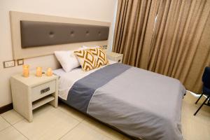 Un dormitorio con una cama y una mesa con velas. en Exquisite 2BD at Skynest Residences with rooftop heated pool en Nairobi
