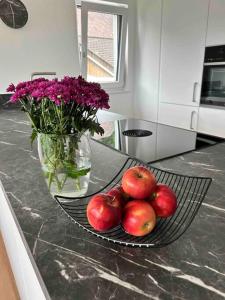 a plate of apples on a counter with a vase of flowers at Ferienwohnung in Neubau in Schellenberg