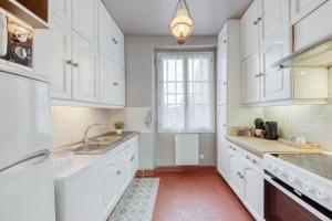 a kitchen with white cabinets and a red floor at Le Lumineux 50 m² Gare/château/wifi/Netflix in Versailles
