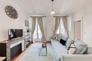 a living room with a couch and a clock on the wall at Le Lumineux 50 m² Gare/château/wifi/Netflix in Versailles
