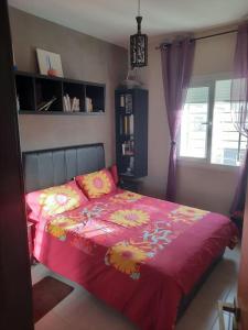 ブズニカにあるAppartement avec piscine à bouznikaのベッドルーム1室(ピンクの毛布と窓付)