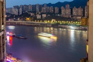 een rivier met gebouwen en 's nachts een stad bij King'sLandind BnB in Chongqing
