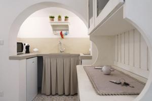 cocina con arco, fregadero y encimera en Le Cementine - Apulian Rooms, en Fasano