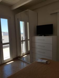 - une chambre avec une télévision et une commode avec un lit dans l'établissement Apartment Colaianni, à Torre San Giovanni