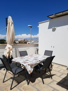 - une table, des chaises et un parasol sur la terrasse dans l'établissement Apartment Colaianni, à Torre San Giovanni