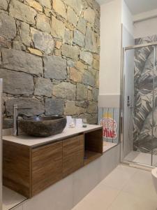 La salle de bains est pourvue d'un mur en pierre et d'un lavabo. dans l'établissement VistaMare & Relax Cinque Terre SeaView & Relax Cinque Terre, à Vernazza