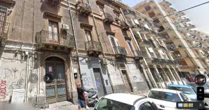 Un uomo in piedi di fronte a un edificio con dei graffiti di City Rooms Katane a Catania