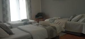 a room with three beds and a chair and a window at Apartman Magnolija in Rijeka