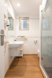 uma casa de banho branca com um lavatório e um chuveiro em Apartamentos Catalina em Es Pujols