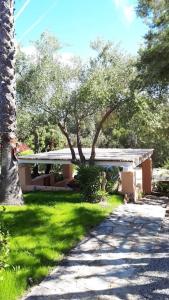 a house with a tree and a sidewalk in the grass at Villa Margiu in Villasimius