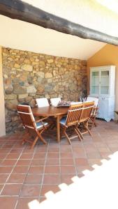 una mesa de madera con sillas y una pared de piedra. en Villa Margiu en Villasimius