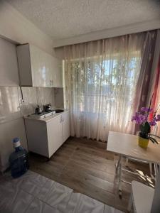 eine kleine Küche mit einem Waschbecken, einem Tisch und einem Fenster in der Unterkunft Duran Apart in Antalya