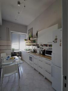 a kitchen with white cabinets and a table in it at DelleArtiGuesthouse Trapani Porto in Trapani