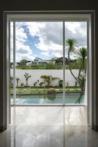 Blick auf den Pool durch ein großes Fenster in der Unterkunft SILENCIO - Bali Invest Club in Canggu