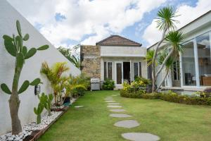 ein Haus mit einem grünen Garten mit Palmen in der Unterkunft SILENCIO - Bali Invest Club in Canggu