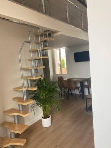 una scala a chiocciola in un ufficio con una pianta in vaso di Duplex type Loft centre ville * clim * WIFI * Haut de gamme * ad Angoulême