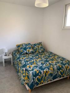 um quarto com uma cama com um cobertor azul e amarelo em Chez Anne em La Ciotat
