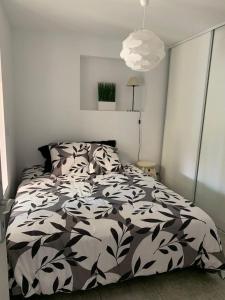 Un dormitorio con una cama con un edredón blanco y negro. en Chez Anne, en La Ciotat