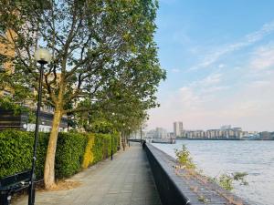 a sidewalk next to the water with trees and a street light at Riverside Premium Double Room E14 in London