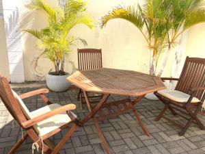 a wooden table and chairs on a patio with palm trees at Tropical getaway villa in Pereybere