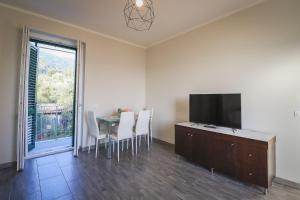 a dining room with a table and a flat screen tv at Appartamento nuovissimo con parcheggio gratuito in Massa