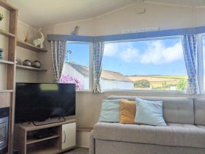 a living room with a couch and a large window at Large 4 person Couples and Family Caravan in Newquay Bay Resort in Newquay