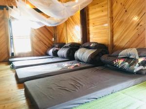 Una fila de sacos de dormir en una habitación con paredes de madera. en Sần's House, en Lào Cai
