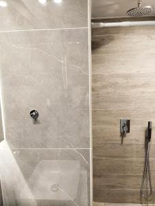 La salle de bains est pourvue d'une douche et d'un mur en pierre. dans l'établissement Vasili's and Vasiliki's luxury apartment, à Athènes