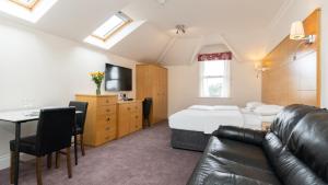 a bedroom with a bed and a couch and a table at Teddington Lodge in Teddington