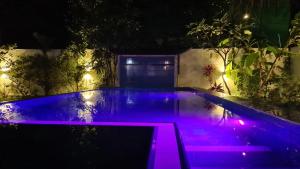 una piscina iluminada por la noche con luces moradas en Emildale Villa, en Wadduwa