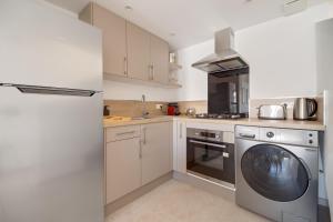 cocina con armarios blancos, lavadora y secadora en Deux suites haut standing duplex proche St. Tropez, en Cogolin