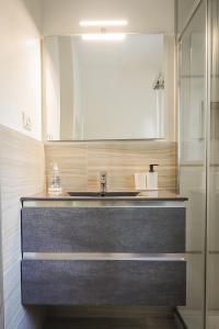 La salle de bains est pourvue d'un lavabo et d'un miroir. dans l'établissement Appartamento nuovissimo con parcheggio gratuito, à Massa